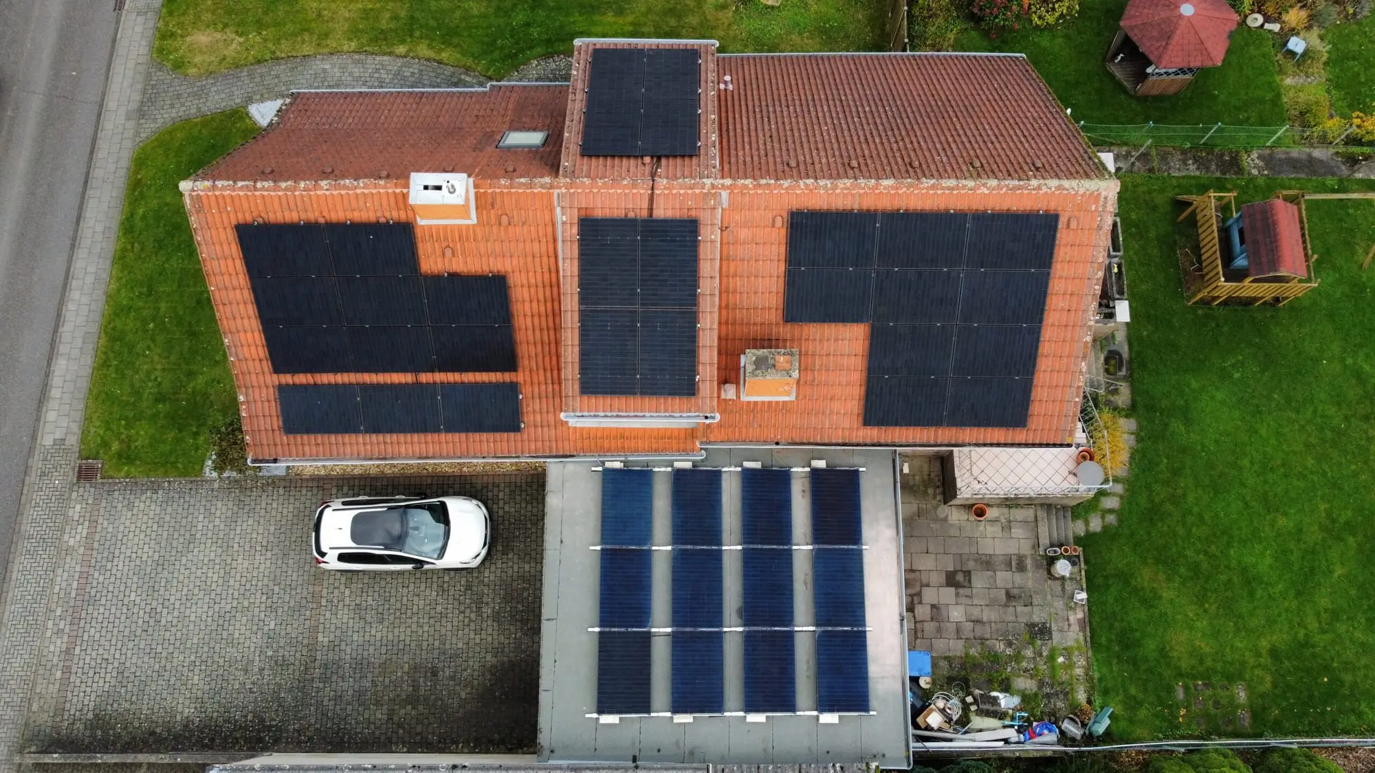 Luftaufnahme eines Wohnhauses mit PV-Modulen auf fünf Dachflächen und dem Garagendach