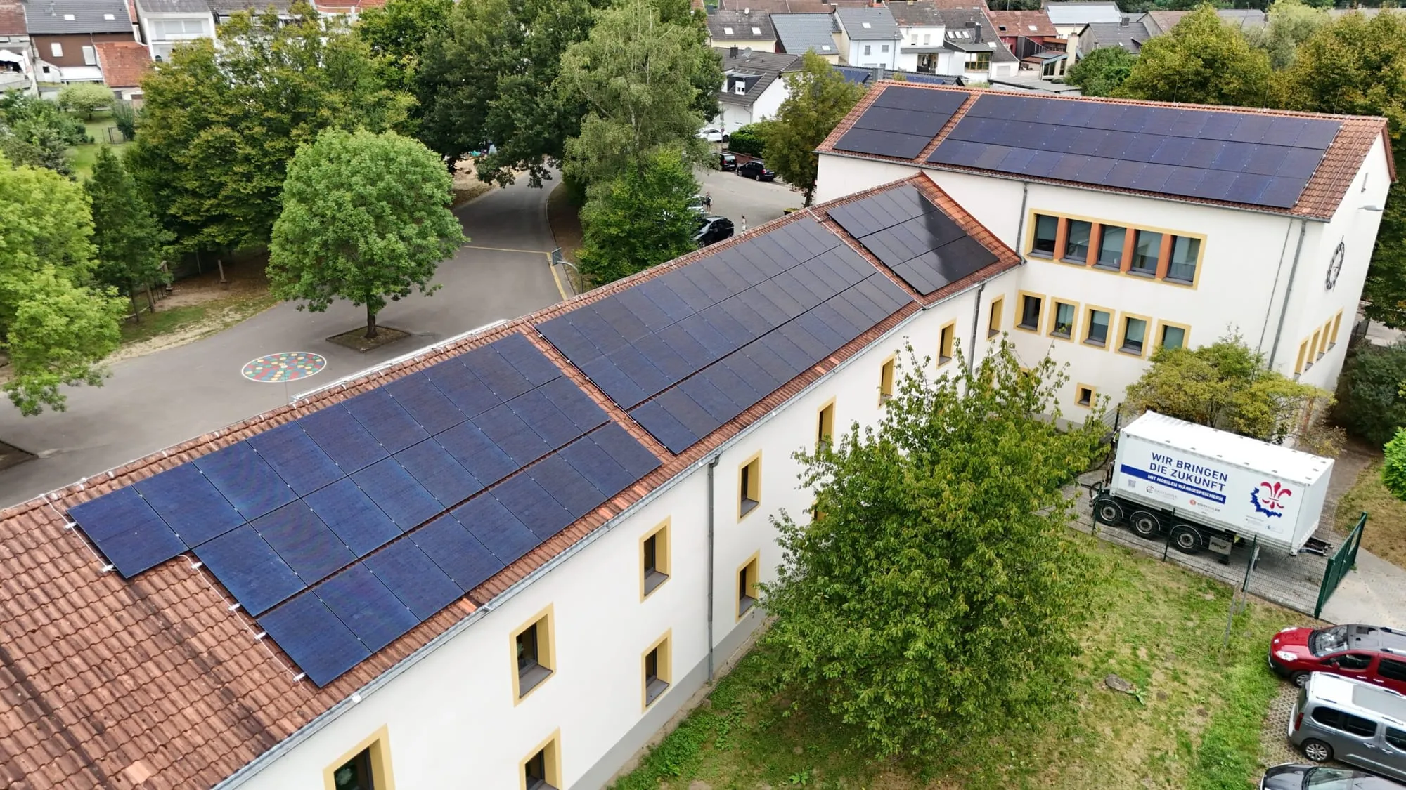 Luftaufnahme einer Schule in Saarbrücken mit Photovoltaik-Modulen auf mehreren Dachflächen