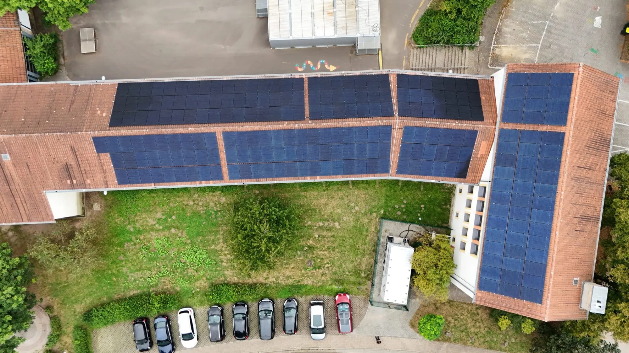 Luftaufnahme der Schuldächer mit PV-Modulen und Schulhof