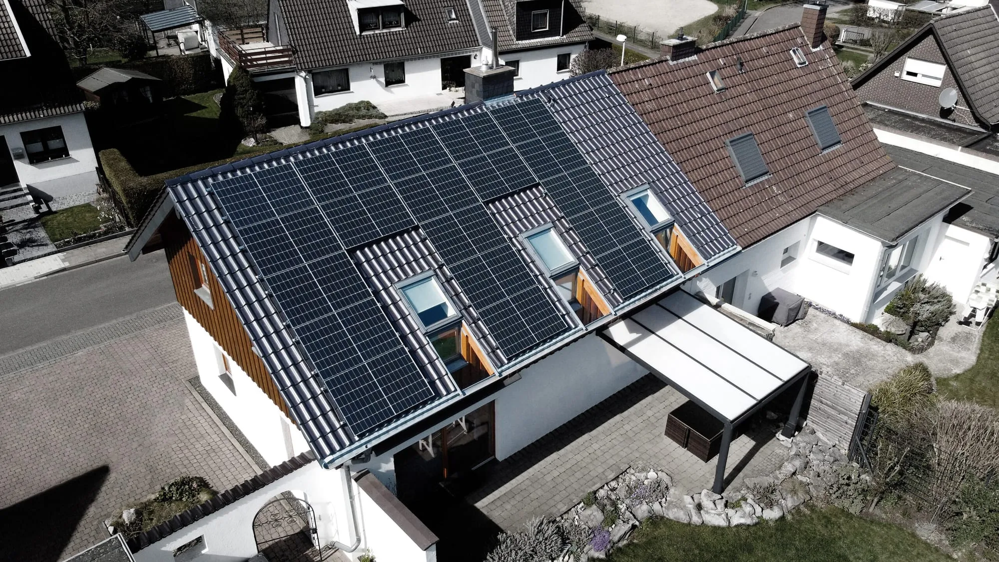 Drohnenaufnahme eines Einfamilienhauses mit PV-Modulen auf beiden Dachseiten und der Garage